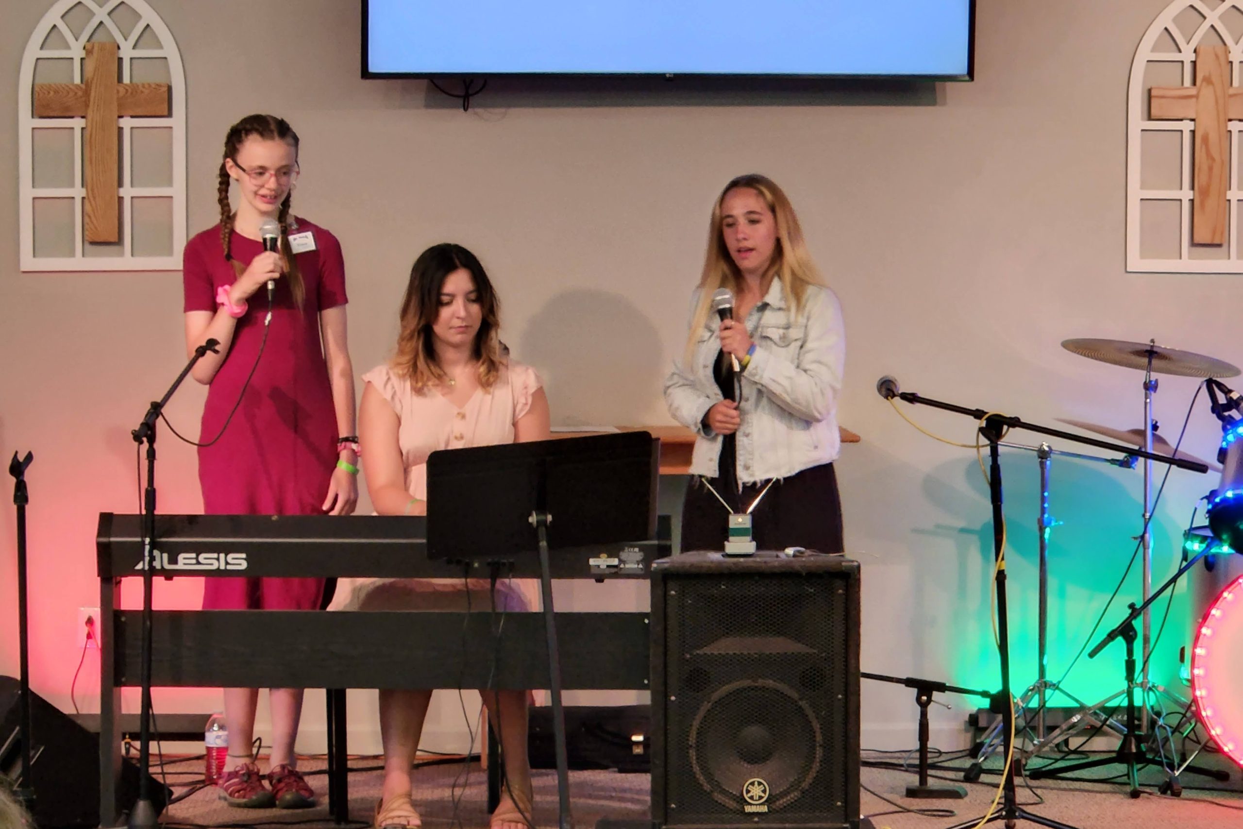 Two high school girls singing a duet, accompanied by an adult pianist