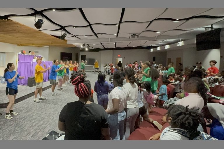 Children in an auditorium participating in a sing-along